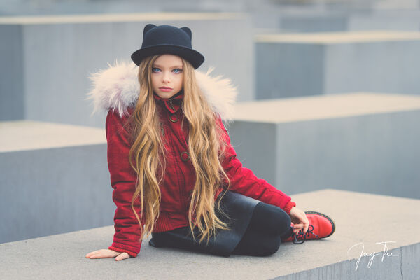 Girl with long blonde hair, red jacket, red shoes and a black hat.