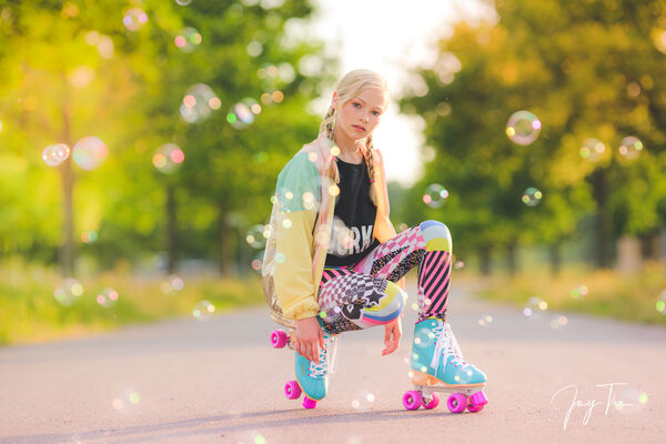 Young girl on a road in a retro outfit with roller skates, surrounded by soap bubbles.