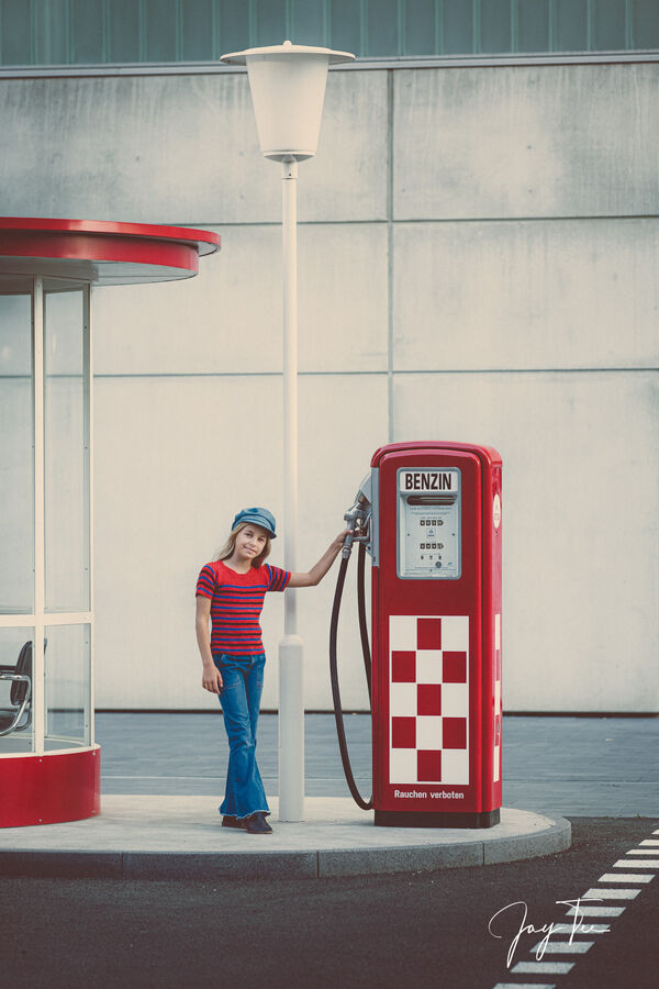 Little girl with flared blue jeans at a retro gas station in germany.