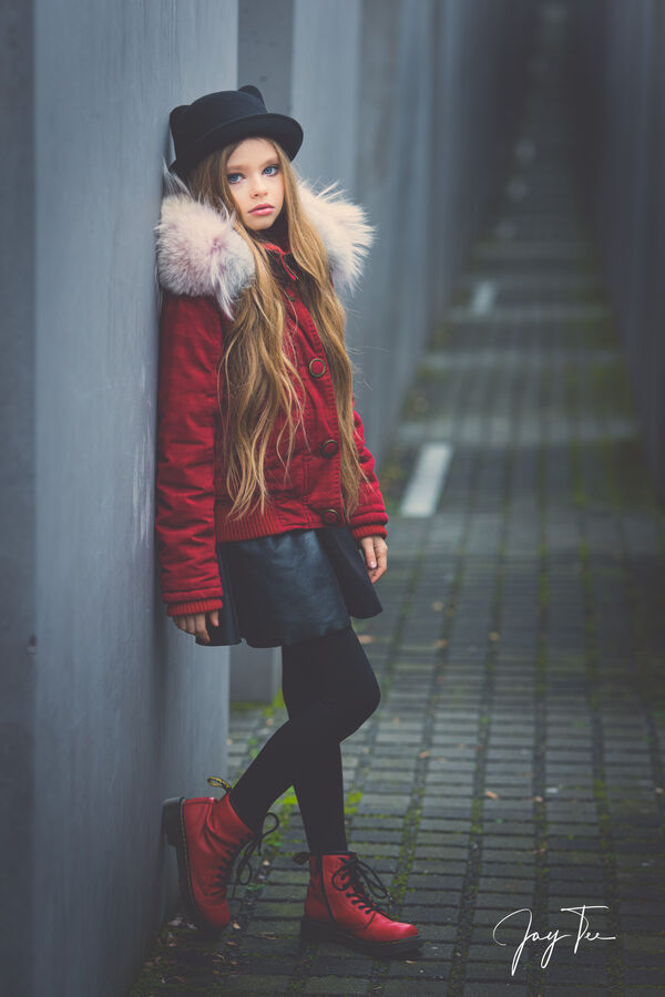 Girl with long blonde hair, red jacket, red shoes and a black hat.