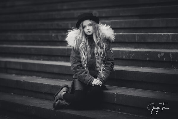 Young girl with long hair is sitting on stairs.