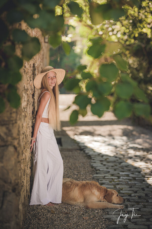 Girl with white pants and a straw hat together with her dog at an old mill in south france.