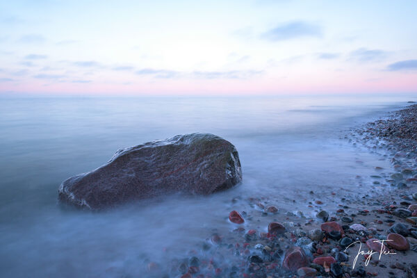 Sonnenuntergang zwischen Warnemünde und Nienhagen. Die Küste ist überseht von kleinen Steinen.