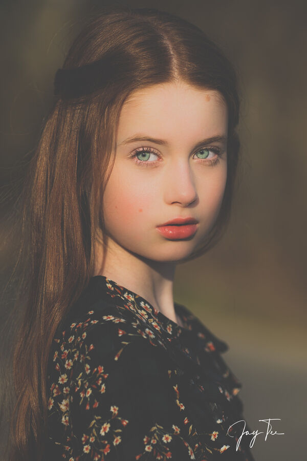 Portrait of a little girl with long ginger hair, green eyes and red lipstick.